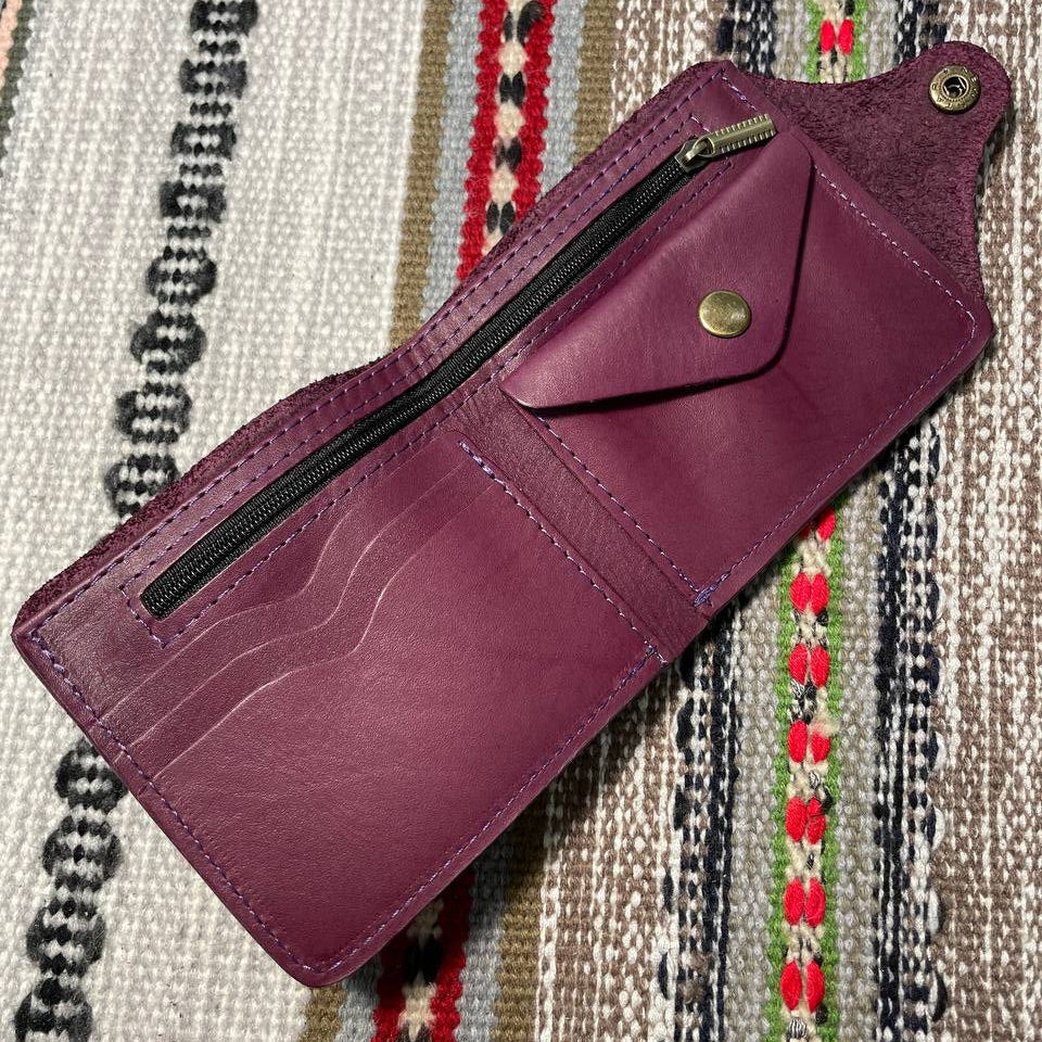 Purple wallet with a strap on a patterned fabric background
