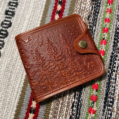 Brown leather wallet with embossed design on a patterned fabric background