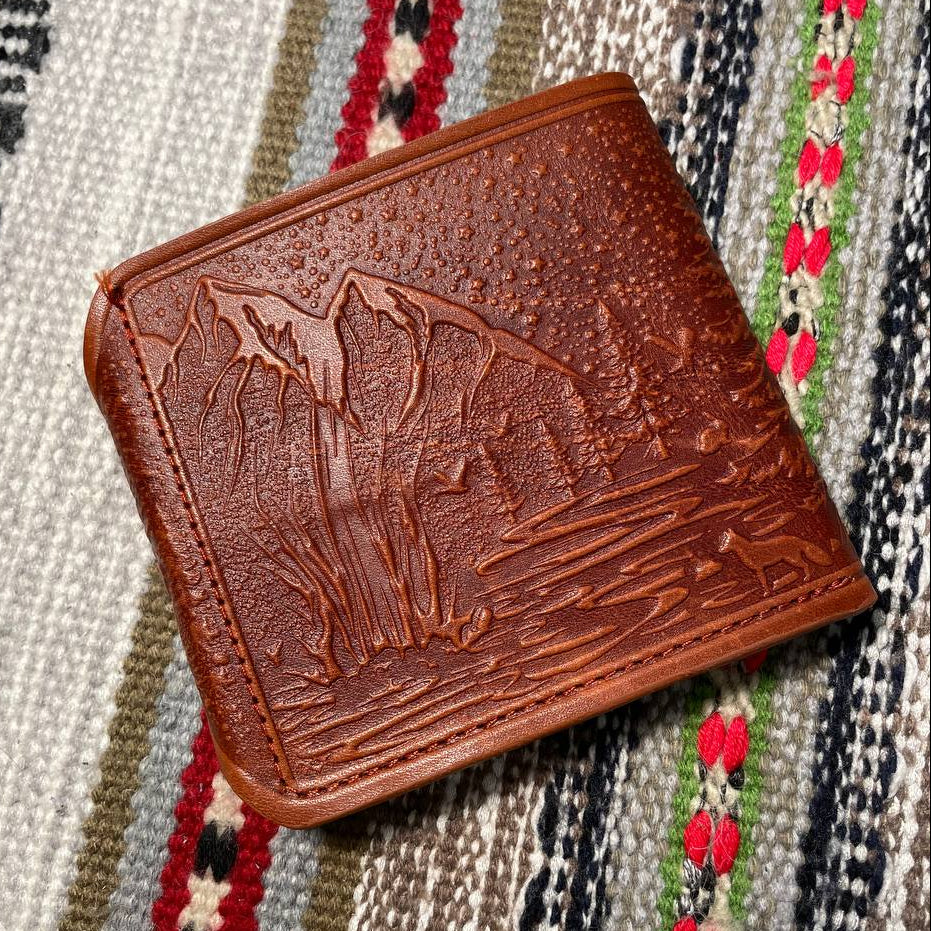 Brown leather wallet with embossed design on a patterned fabric background