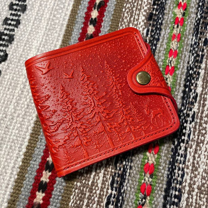 Red textured wallet with a metal buckle on a patterned fabric background