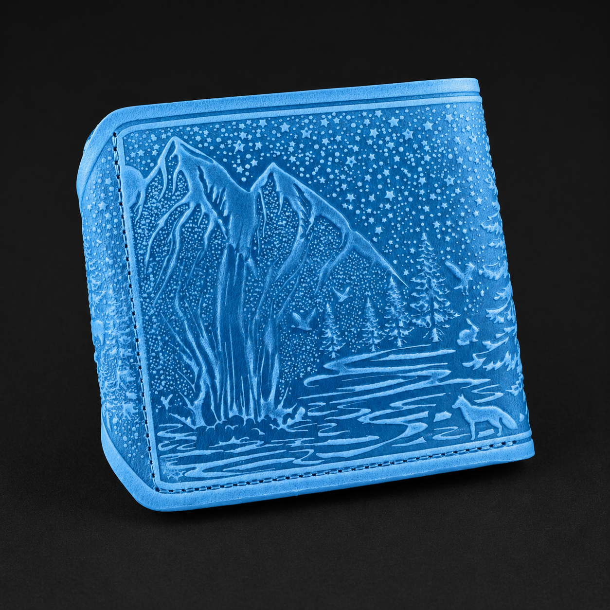 Blue wallet with engraved landscape design on a black background