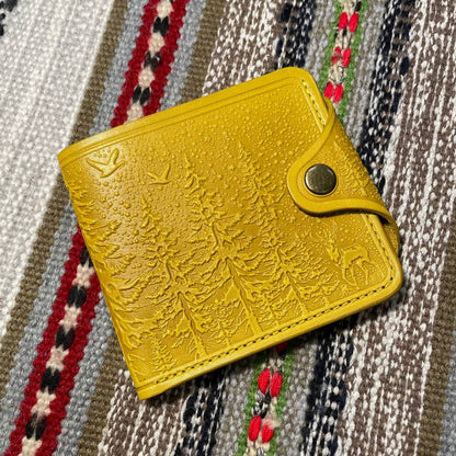 Yellow textured wallet with a metallic clasp on a patterned fabric background