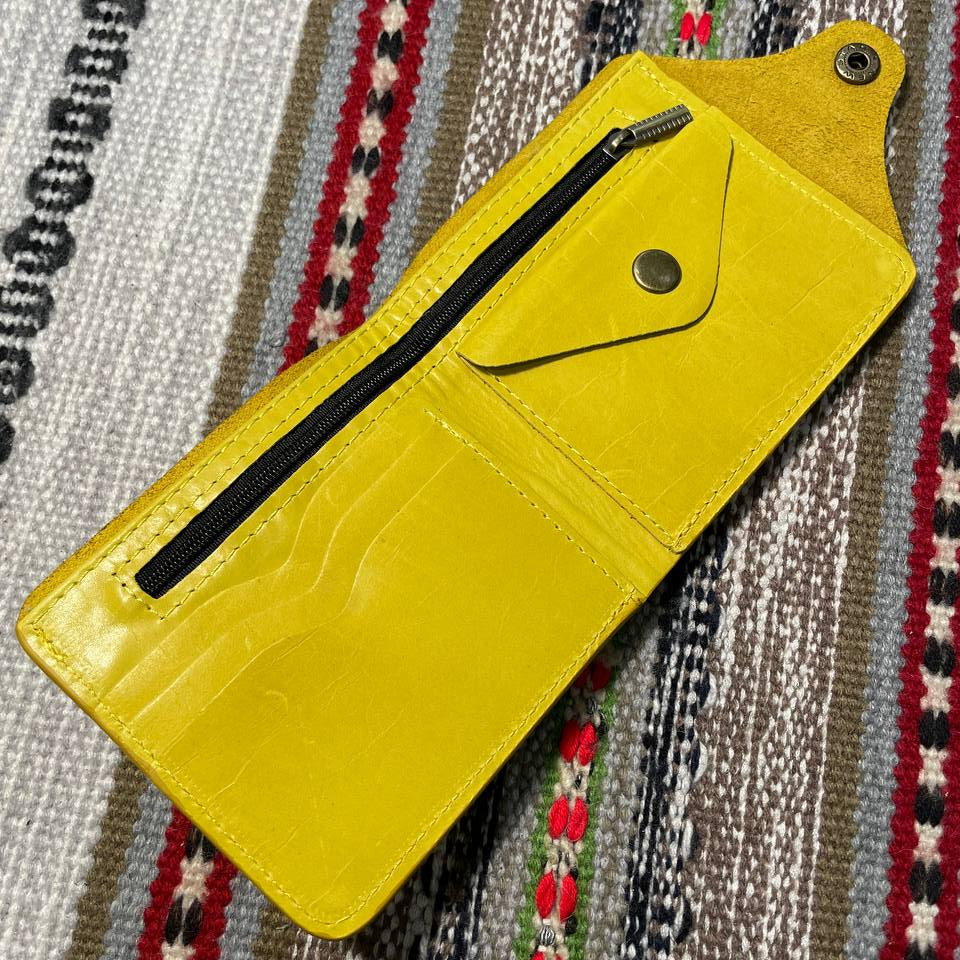 Yellow wallet with a zipper on a patterned fabric background